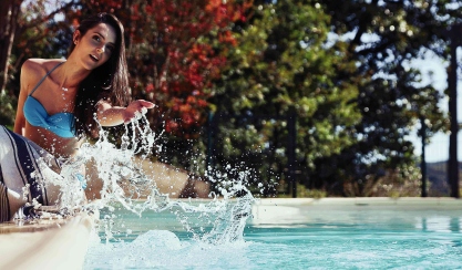 Woman sitting beside a pool with a striped linen towel