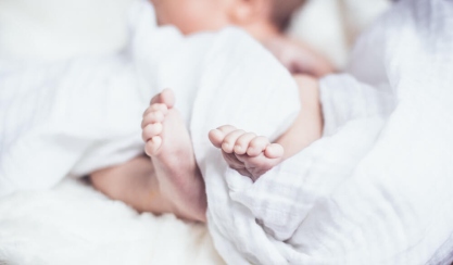 Baby's feet wrapped in white bedding