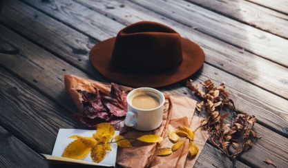 Autumn leaves, coffee and felt hat on wooden boards
