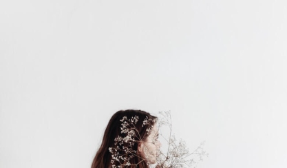 Woman in a white linen shirt holding dried flowers